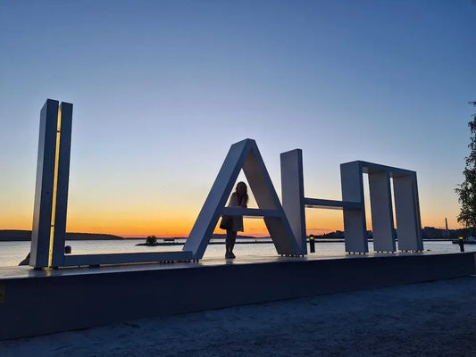Lahti kyltti auringon laskiessa järven rannassa