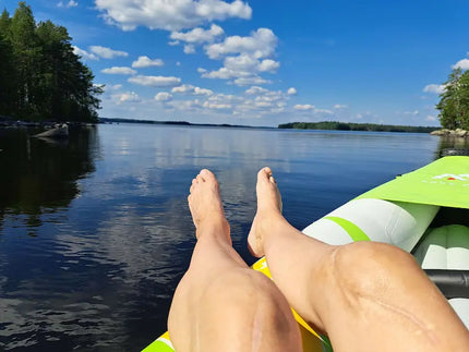 Arpiset polvet ja jalkaterät rennosti kajakin reunalla järvimaisemassa