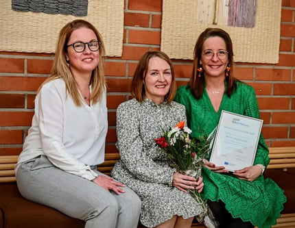 Vaicute-luonnonkosmetiikkaa valmistava naisyrittäjäkolmikko istumassa kukkien ja kunniakirjan kanssa. Elävä Kainuu Leaderin Vuoden Yritystoimenpide 2024 palkinto. Marion Finland Oy:lle.